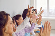 © Studio Romantic - Audience raising hands to ask questions. Group of people raising hands at a business conference. Team of diverse women putting up hands to ask the speaker questions after a business presentation