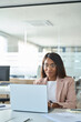 © insta_photos - Young busy professional African American business woman working with corporate data on laptop in office, female company marketing manager executive using computer technology sitting at desk.