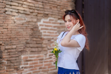 Wall Mural - Pretty Asian tourists woman wearing beautiful hand-woven clothes dyed with indigo and mud-fermented natural colors modern Thai traditional dress costumes are popular in ancient temple Thailand.