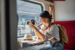 © Natee Meepian - Beautiful Asian female tourist with sitting and take a photo travel location and sightseeing urban window view, public train transport, city lifestyle journey by railway