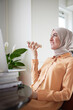 © Johnér - Smiling woman with hijab have conversation with colleague or friend on speaker mode