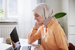 © Johnér - Smiling woman with hijab working from home using laptop