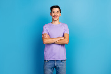 Wall Mural - Casually handsome. Confident young handsome man in t shirt keeping arms crossed smiling standing against blue background