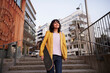 © Johnér - Low angle view of woman walking down stairs and carrying skateboard