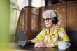 © Johnér - Senior woman in headphones using tablet