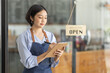 © David - Startup successful small business owner sme beauty girl stand with tablet smartphone in coffee shop restaurant. Portrait of asian tan woman barista cafe owner. SME entrepreneur seller business concept