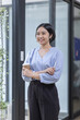 © David - Young asian woman, professional entrepreneur standing in office clothing, smiling and looking confident, workplace office background