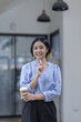 © David - Young asian woman, professional entrepreneur standing in office clothing, smiling and looking confident, workplace office background