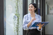 © David - Boring young business Asian woman holding document file and looking at camera stand on a workplace office.