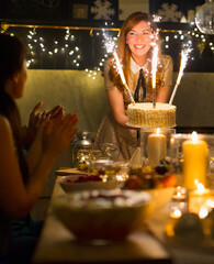 Enthusiastic woman serving cake sparkler fireworks to clapping friends