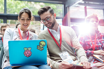 Wall Mural - Man and woman using laptop in audience at technology conference