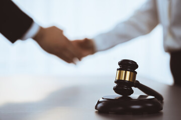 Wall Mural - Focus gavel symbolize justice on blur background of lawyer colleagues handshake after successful legal deal for lawsuit to advocate resolves dispute in court ensuring trustworthy partner. Equilibrium