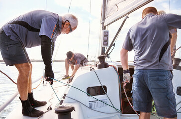 Wall Mural - Men sailing adjusting sailboat rigging