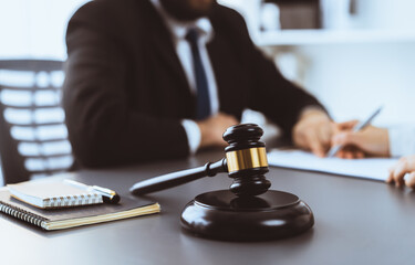 Poster - Focus closeup wooden gavel on blur background of lawyer colleagues or drafting legal documents on their workplace at law firm office. Hammer of justice for righteous and equality judgment. Equilibrium