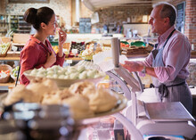 Deli Worker Offering Cheese Sample To Woman In Market