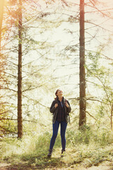 Canvas Print - Smiling woman hiking looking up at sunny trees in woods