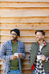 Wall Mural - Smiling men drinking coffee outside cabin