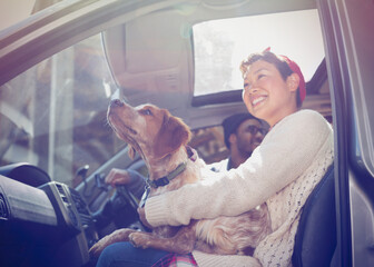 Smiling woman holding dog on lap in car