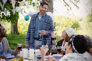 Man toasting friends at garden party table