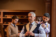 Tailors fitting businessman for suit in menswear shop