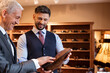 © KOTO - Worker showing dress shoes to businessman in menswear shop