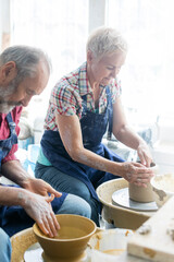 Wall Mural - Senior couple using pottery wheels in studio