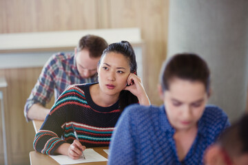 Wall Mural - Pensive female college student taking test in classroom