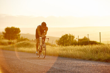 Canvas Print - Male triathlete cyclist cycling on sunny rural road at sunrise