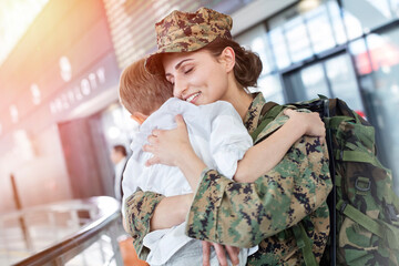 Wall Mural - Son greeting and hugging soldier mom at airport