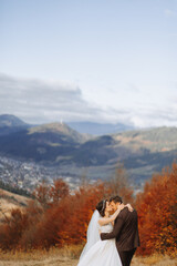 Wall Mural - Loving couple in the mountains. Weddings in the mountains. Back view of the newlywed couple standing on the mountains and enjoying the landscape.