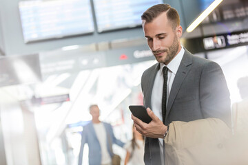 Wall Mural - Businessman texting with cell phone in airport concourse