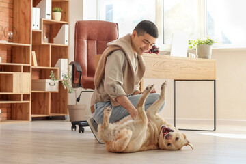 Wall Mural - Young man with cute Labrador dog in office