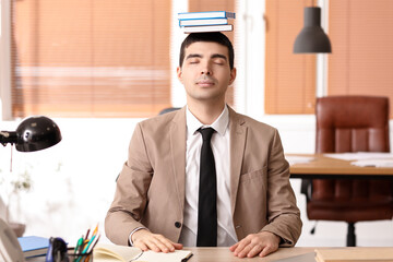 Poster - Young businessman with books meditating in office. Balance concept