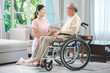 © chokniti - Asian family health care and insurance business at home concept, woman daughter take care support to senior elderly father patient in wheelchair together, dad having smile in happy love lifestyle