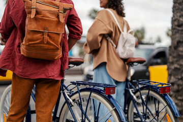 cropped picture of two tourists with eco friendly rental rides waiting on the street to cross the ro