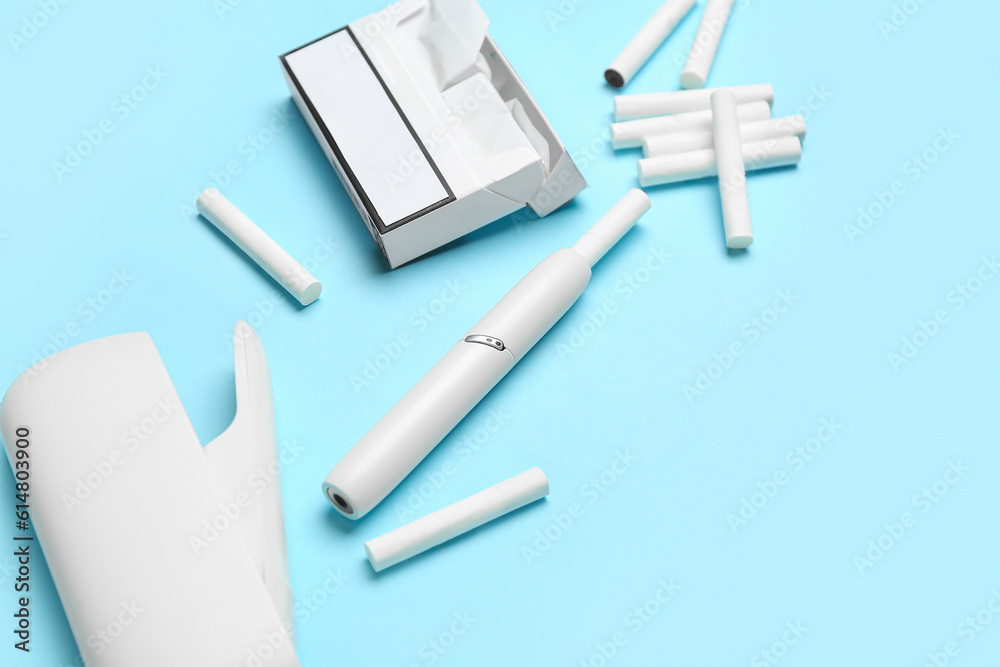 Modern electronic cigar, pack and sticks on blue background