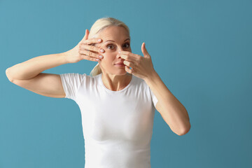 Canvas Print - Mature woman doing face building exercise on blue background