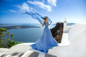 Elegant luxury evening fashion. Glamour, stylish elegant woman in long gown dress is posing outdoor in luxury resort in Santorini. Female model in amazing long dress. Vogue. Couture.