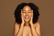 © Prostock-studio - Thrilled pretty young black woman touching her face and laughing