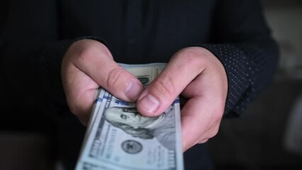 Wall Mural - Close-up of male hands pulling pack of one hundred dollar bills trying to pay for deal and make purchase, on blurred dark background. Bribery and corruption concepts. Financial business concept. 