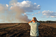 A Man, Who Has His Back Turned, Medium Shot, Looks At His Burned Field.