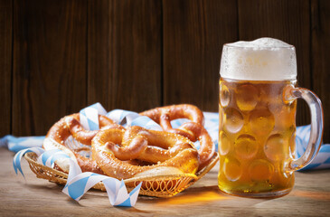 Wall Mural - Mug of beer and basket of pretzels on wooden background. Oktoberfest, beer festival