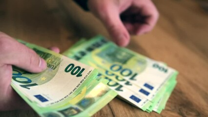 Wall Mural - Men's hands counting 100 euro bills, carefully laying them out in an even pile against the background of a wooden table, close up. Financial management concept.