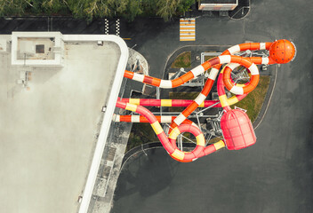 Aerial top down view of colorful winding slides of an attraction in indoor aquapark. Modern building of entertainment center with aquapark