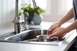 © Margo_Alexa - Close up hands of housewife washing dishes in at the kitchen sink.Generative AI