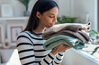 Beautiful woman smelling clean laundry after folding in living room at home