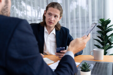 Two corporate colleagues collaborate and discussing idea together in meeting room. Business people planning business work in professional working environment. Modern office workplace. Entity