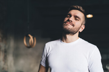 Wall Mural - Positive young man standing with half closed eyes in gym