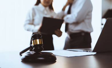 Wall Mural - Focus closeup wooden gavel on blur background of lawyer colleagues or drafting legal documents on their workplace at law firm office. Hammer of justice for righteous and equality judgment. Equilibrium