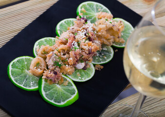 Sticker - Fried calamari and sepia in batter of tempura flour and sesame on cushion of pickled limes with glass of wine